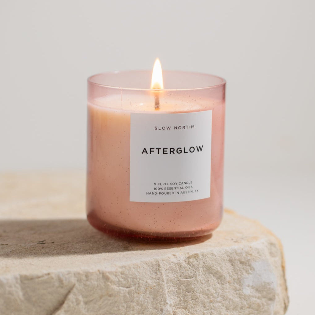 Pink candle labeled 'Afterglow' on a light stone surface with a neutral background