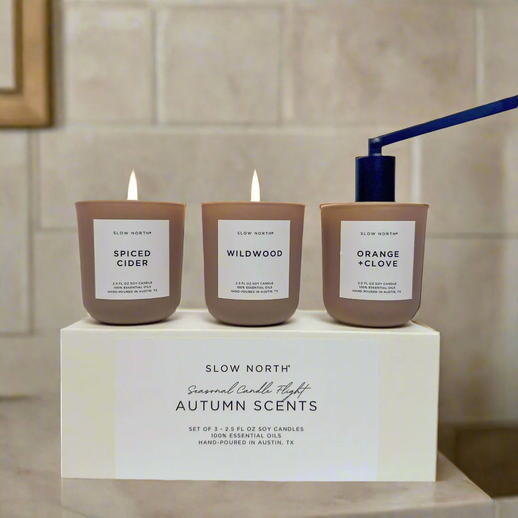 Three candles with labels on a box labeled 'Slow North' on a white background