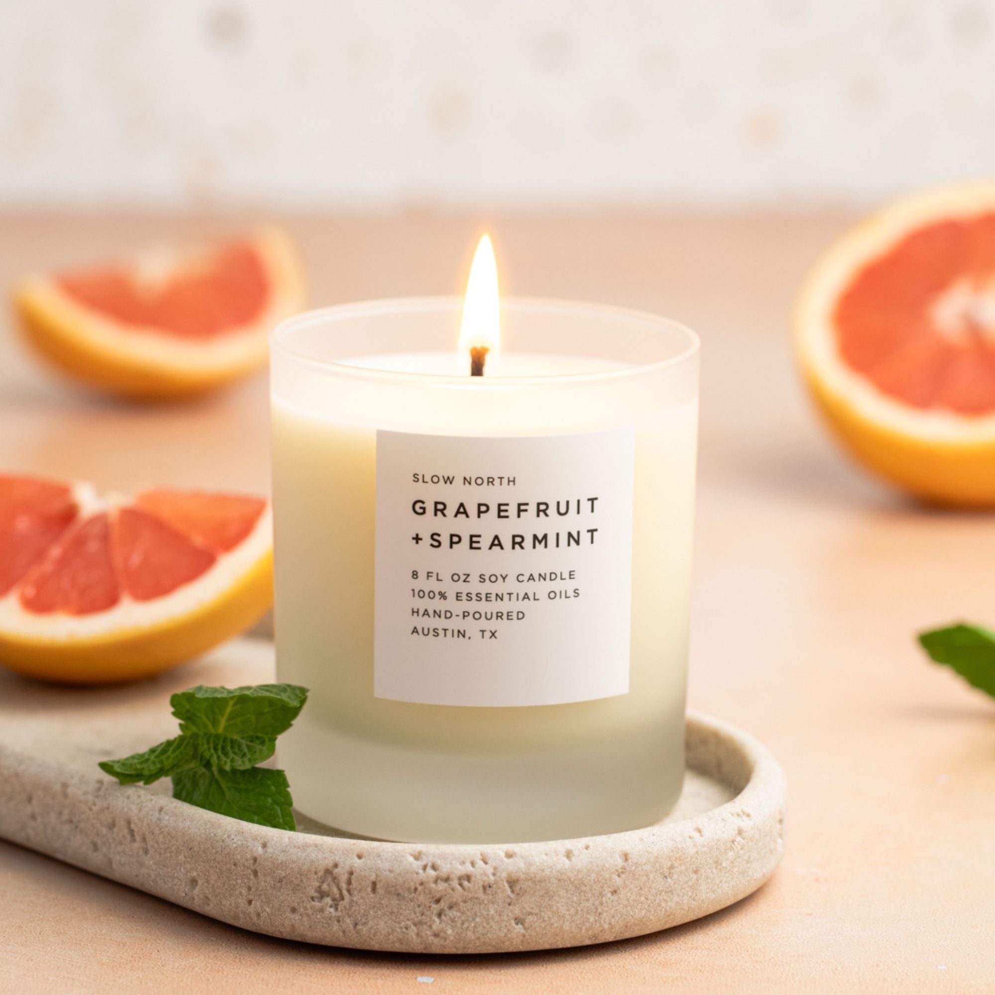 Grapefruit and spearmint candle on a stone tray with grapefruit slices in the background