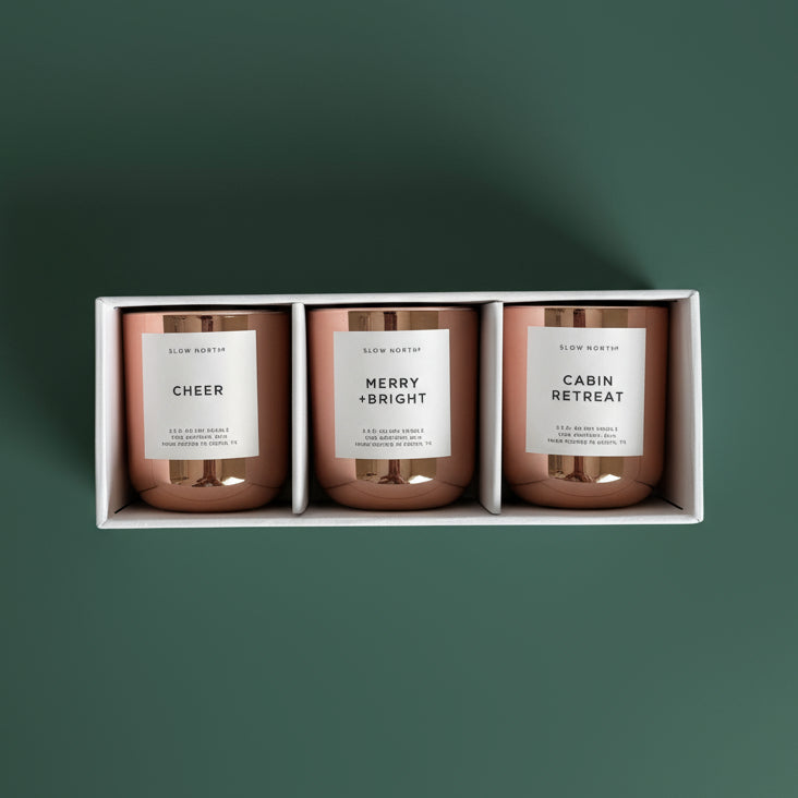 Three candles in a box with labels 'Cheer', 'Merry & Bright', and 'Cabin Retreat'.
