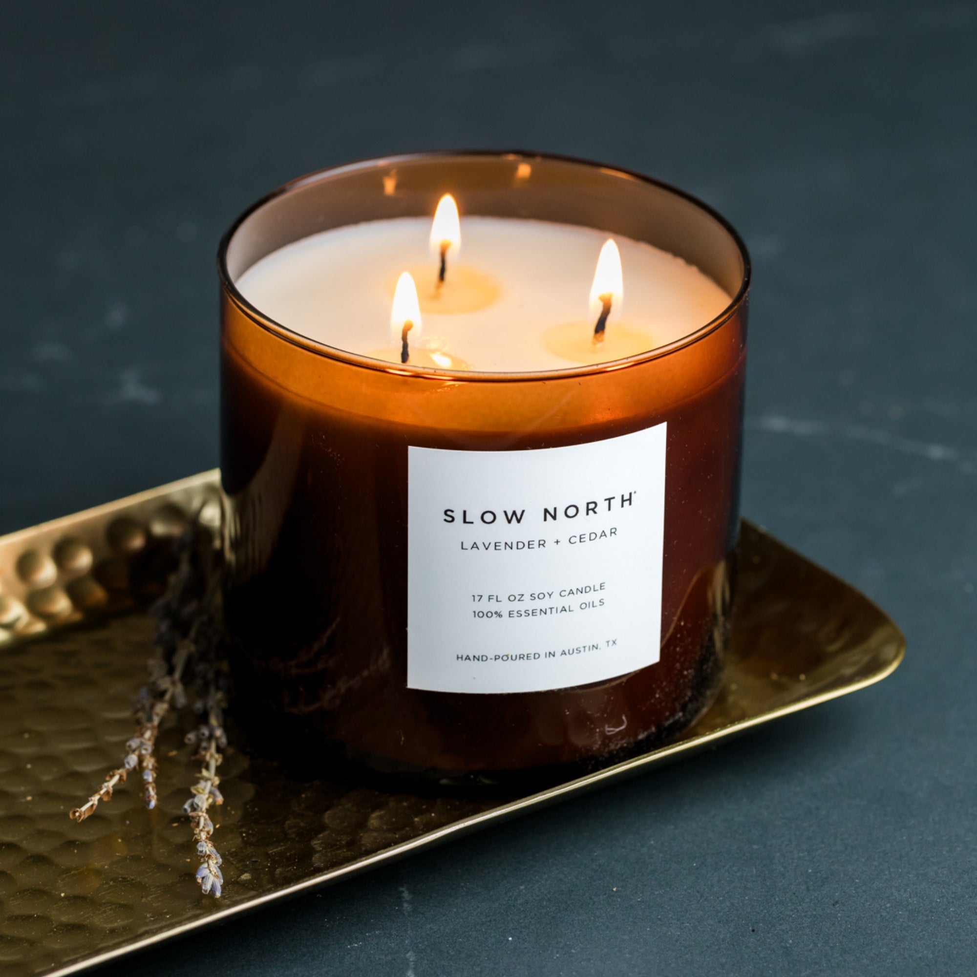Three-wick candle labeled 'Slow North' on a dark background