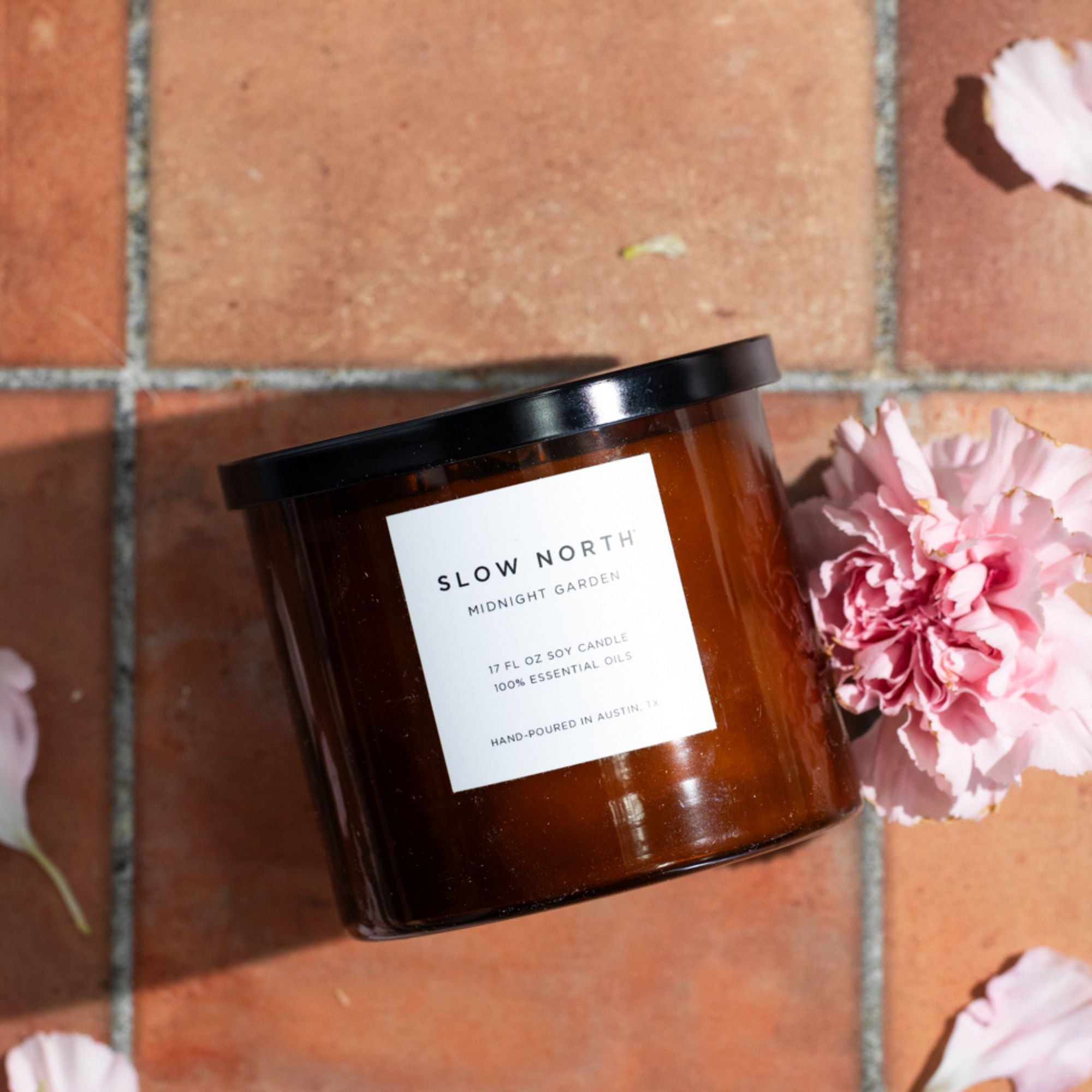 Natural Candle with 'Slow North' label on a brick wall background