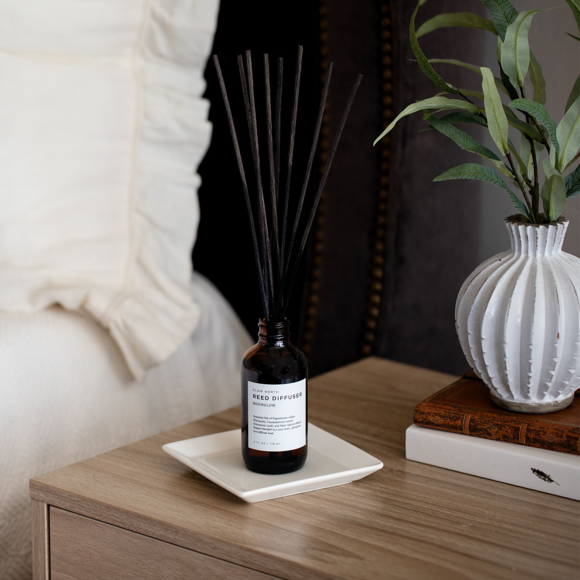 Room Diffuser bottle on a wooden surface with a plant and books in the background