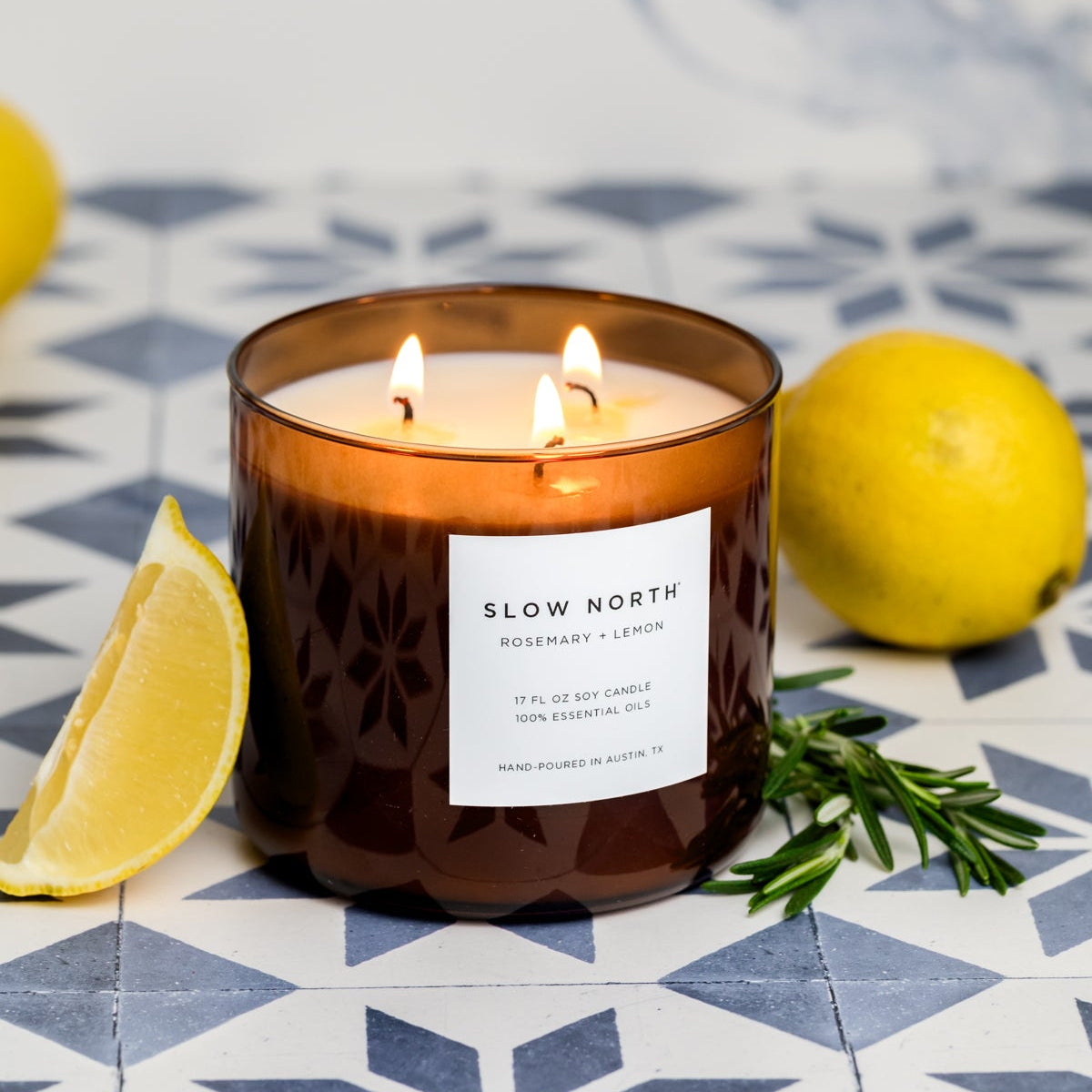 Candle with a label on a patterned surface with lemons and rosemary