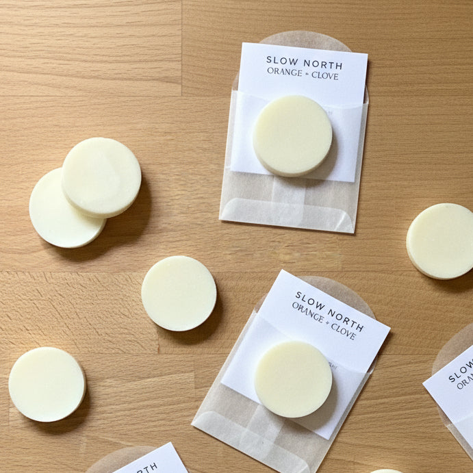 Three wax melts on a wooden surface with a 'Slow North' label.