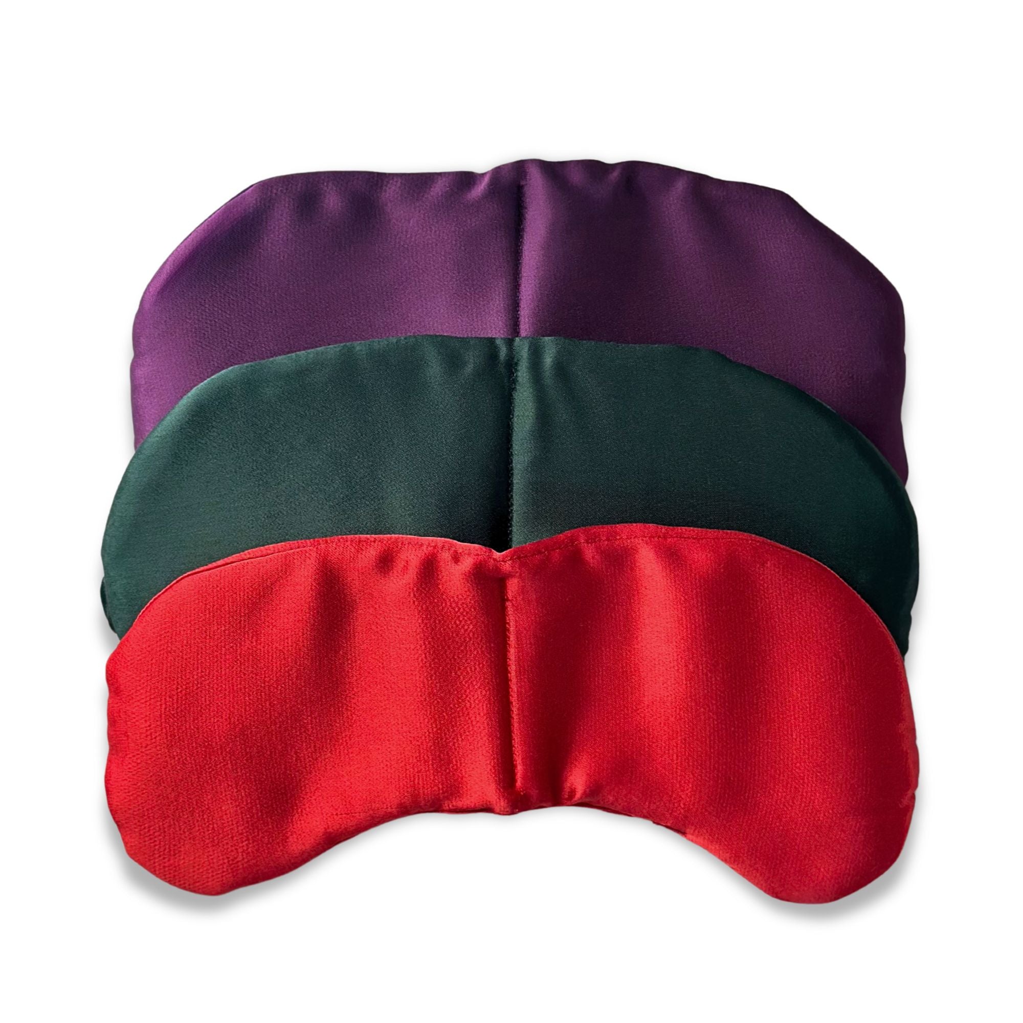 Three satin eye masks in purple, green, and red on a white background