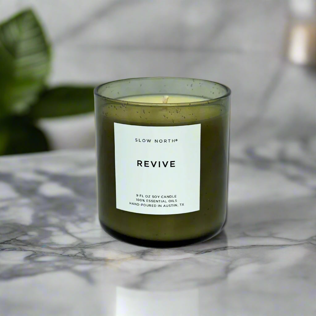 Green candle labeled 'Revive' by Slow North in a spa
