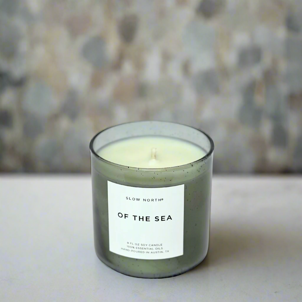 Soy Candle in a glass jar with a label on a stone background