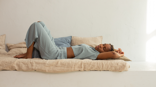 woman lays on a mattress daybed with arms folded overhead