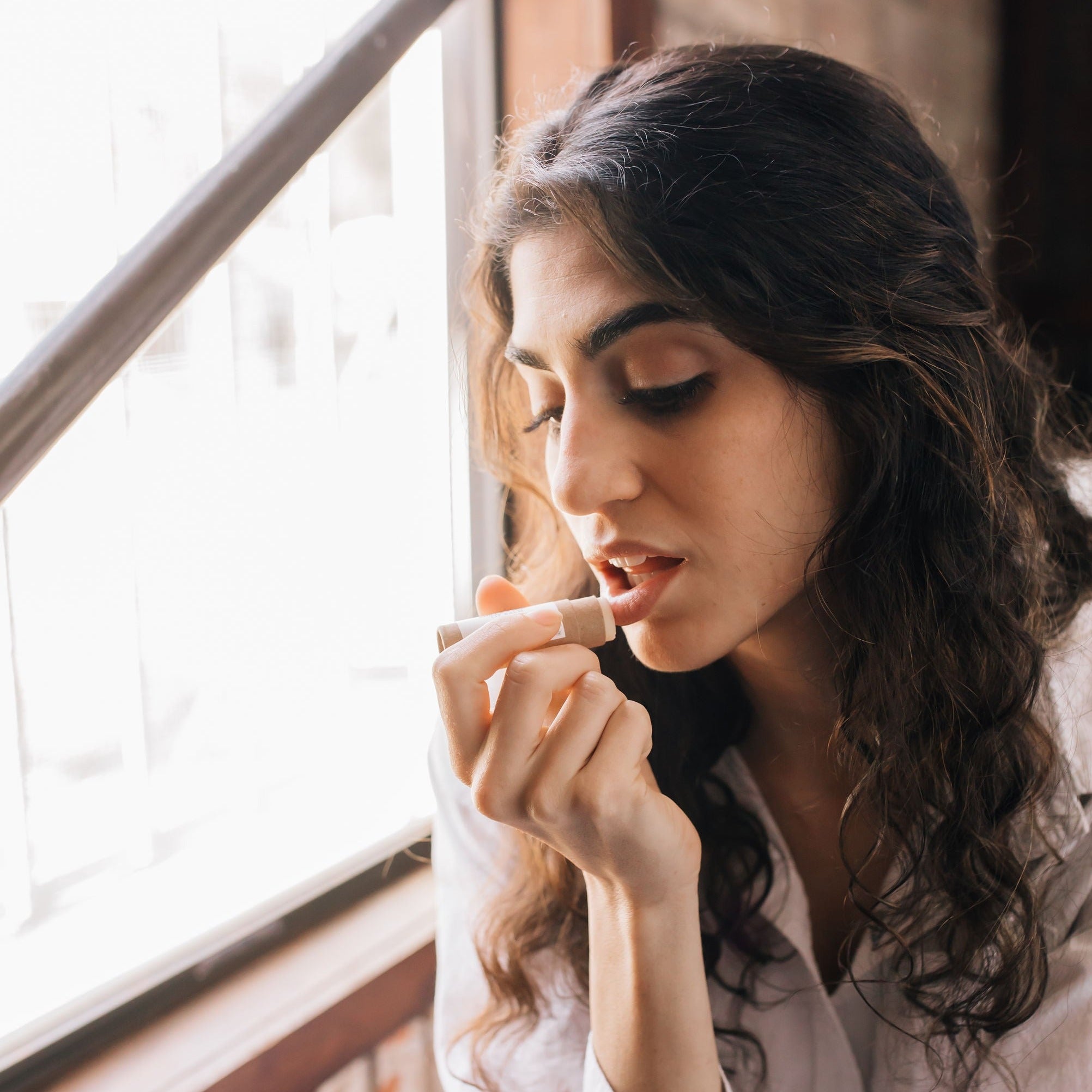 woman applying natural lip balm to lips