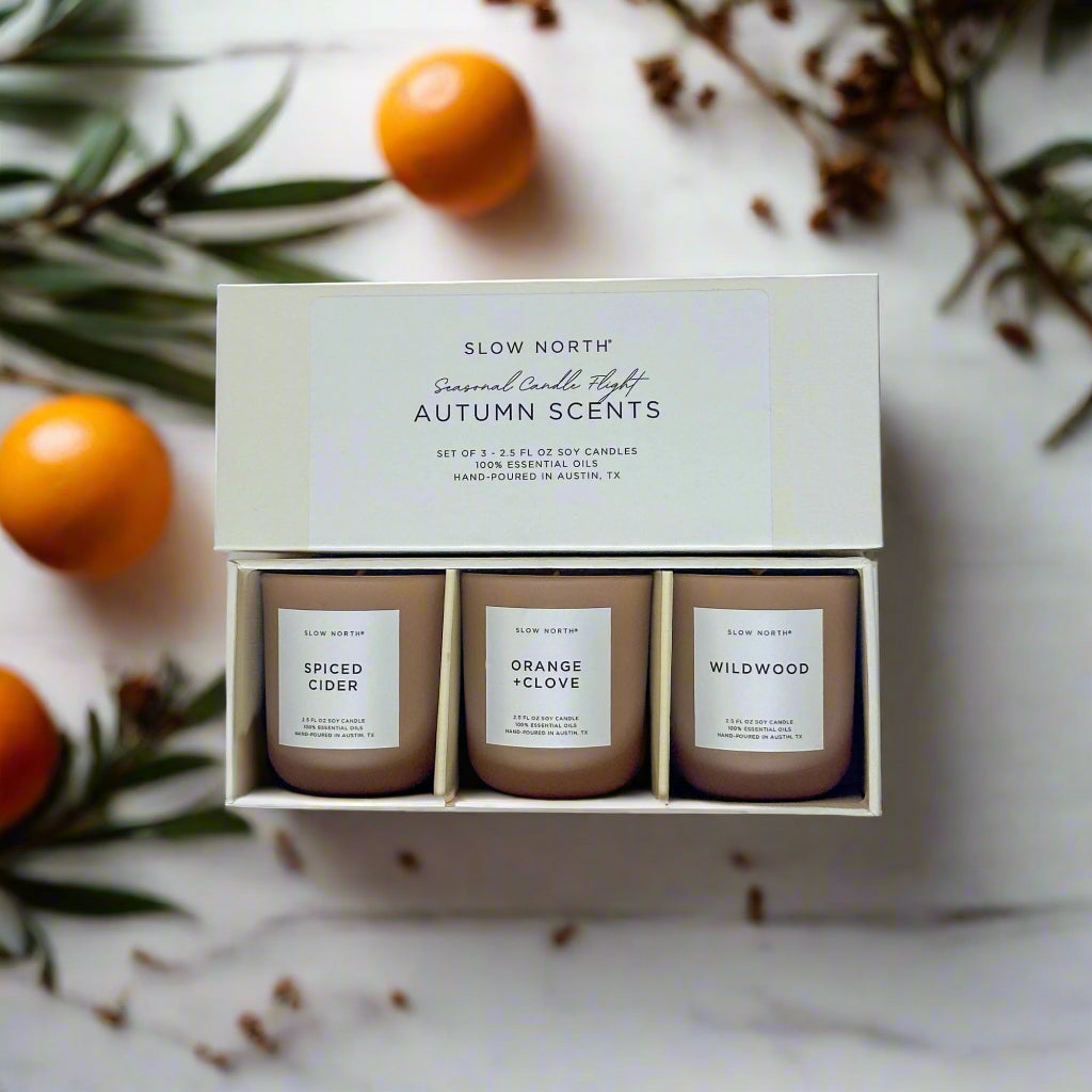 Set of three candles in a box labeled 'Autumn Scents' by Slow North on a light background.