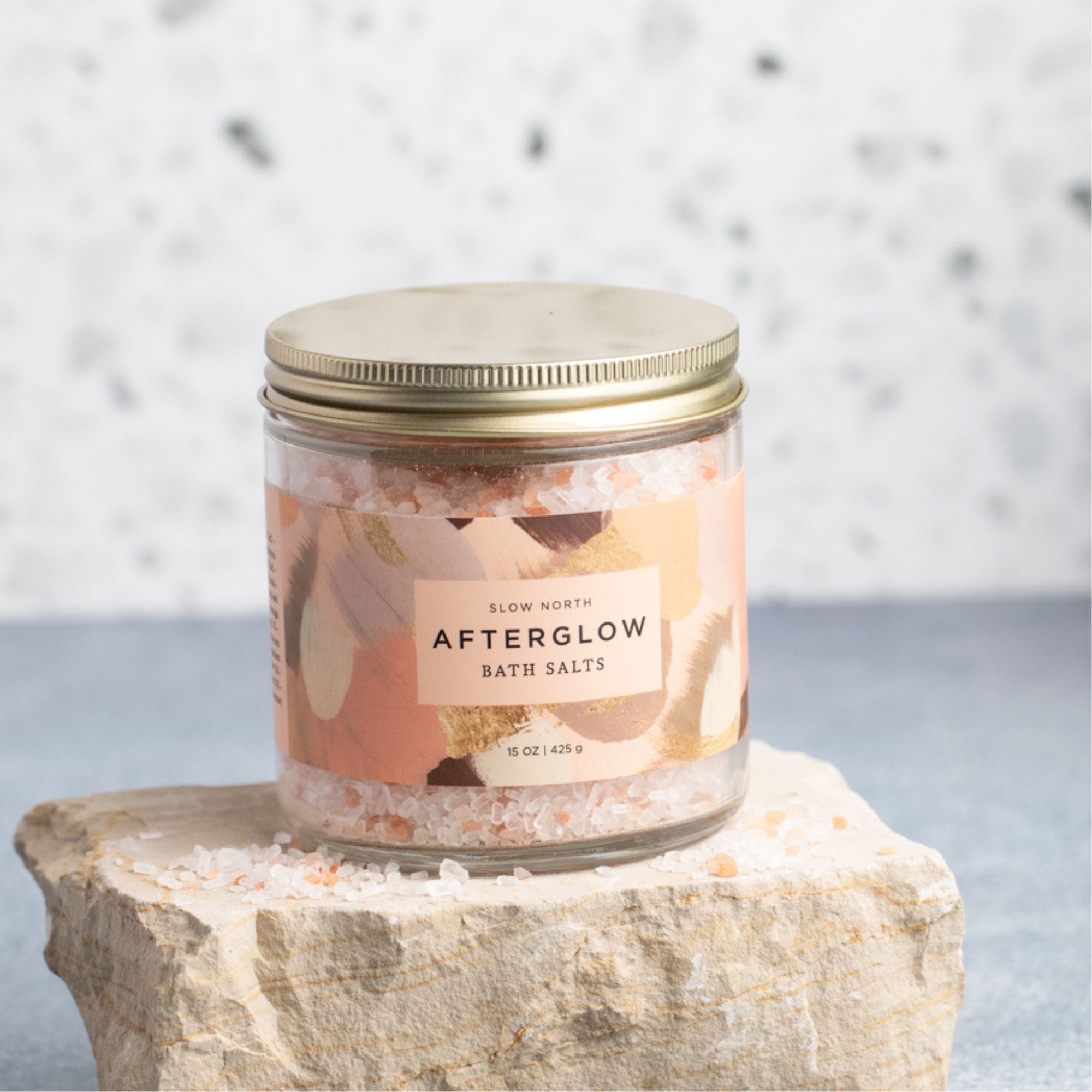 Jar of 'Afterglow' bath salts on a stone surface with a neutral background