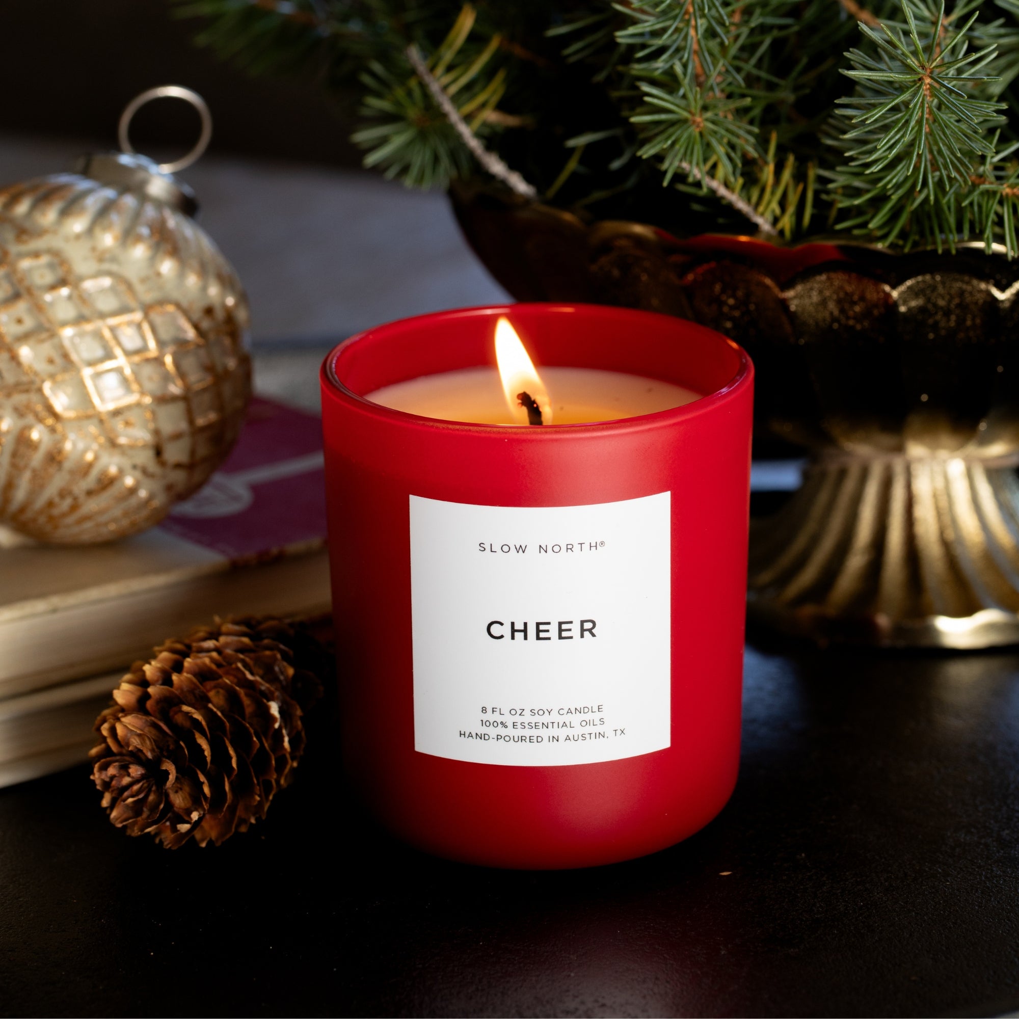 Red candle labeled 'CHEER' with Christmas decorations in the background