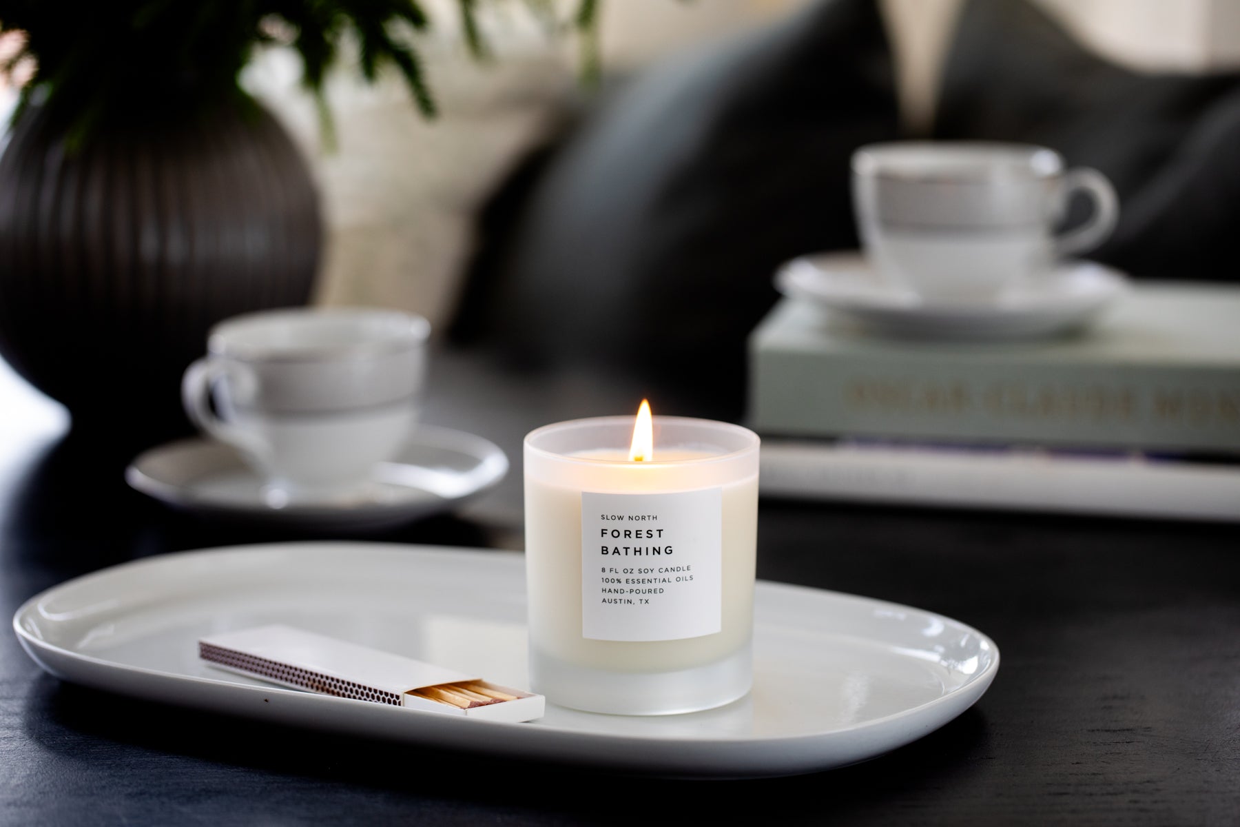 Candle on a white plate with a blurred background of a cozy setting