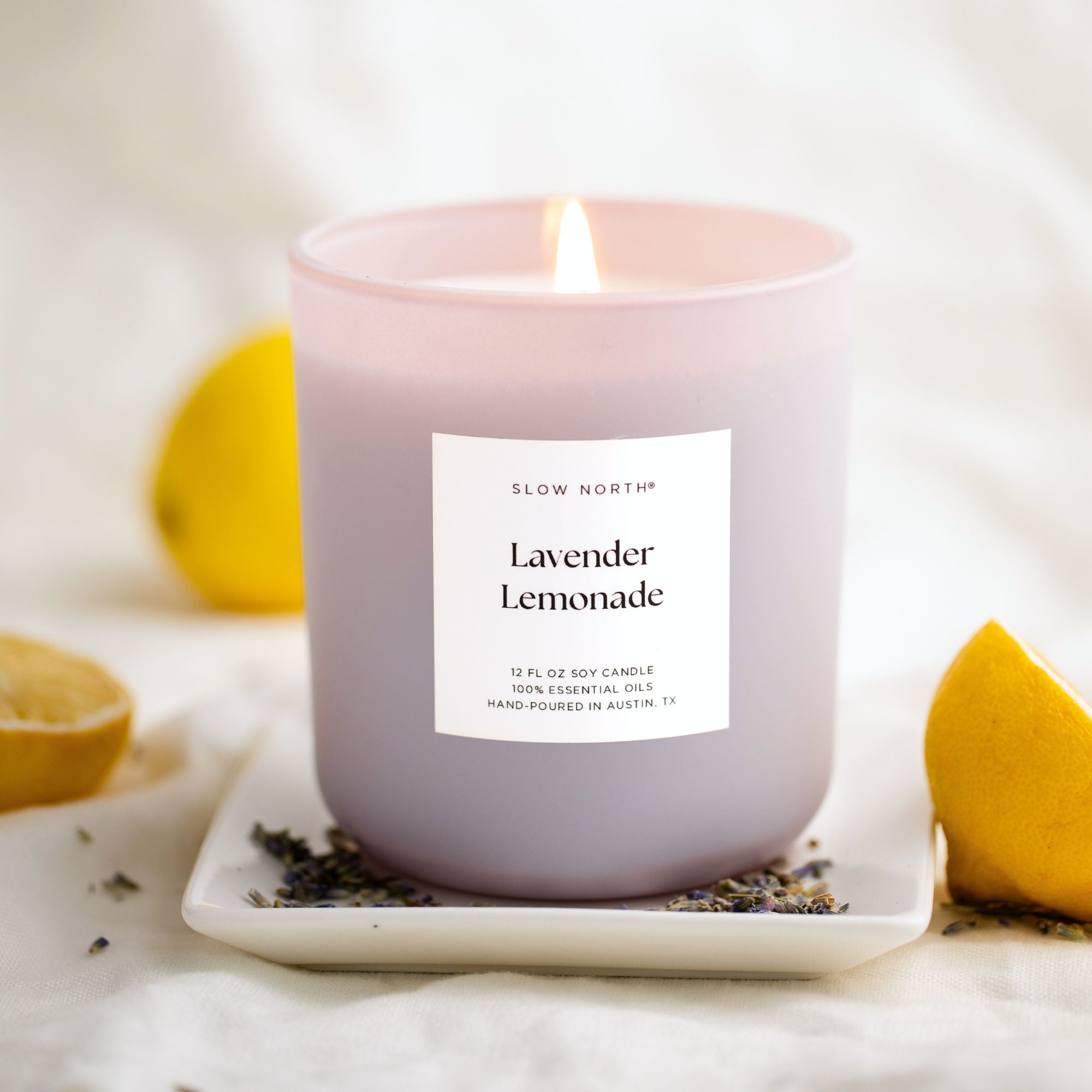 Lavender Lemonade candle with a label on a white plate surrounded by lemons and lavender buds.