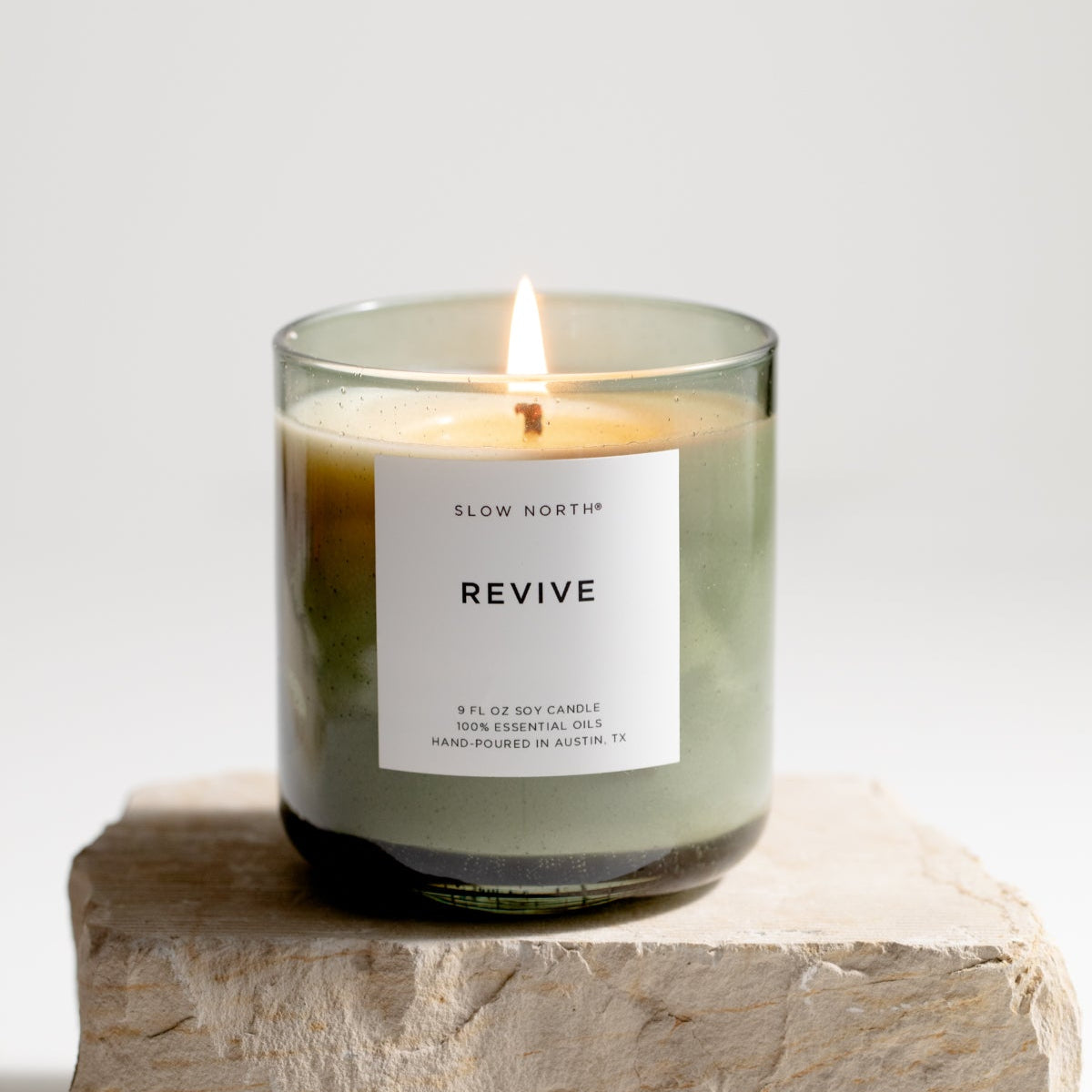 Candle labeled 'Revive' on a stone block with a white background