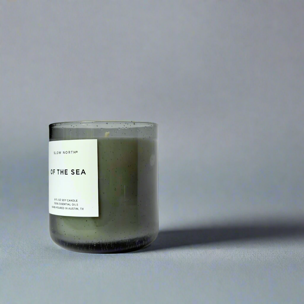 Candle labeled 'Of the Sea' on a smokey blue background