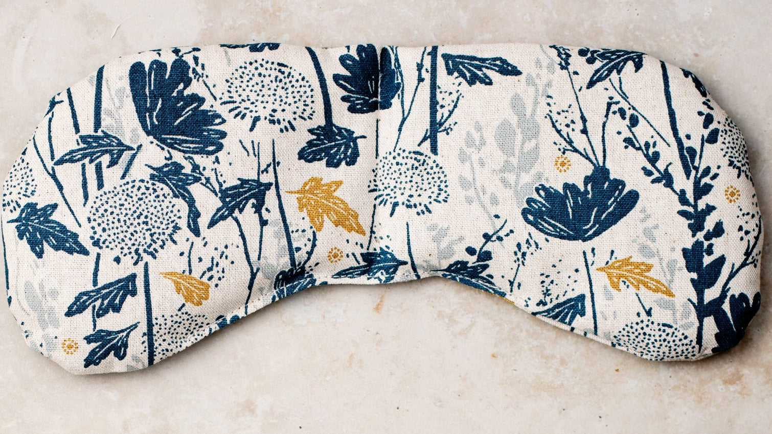 Floral-patterned eye mask and neck pillow on a neutral background