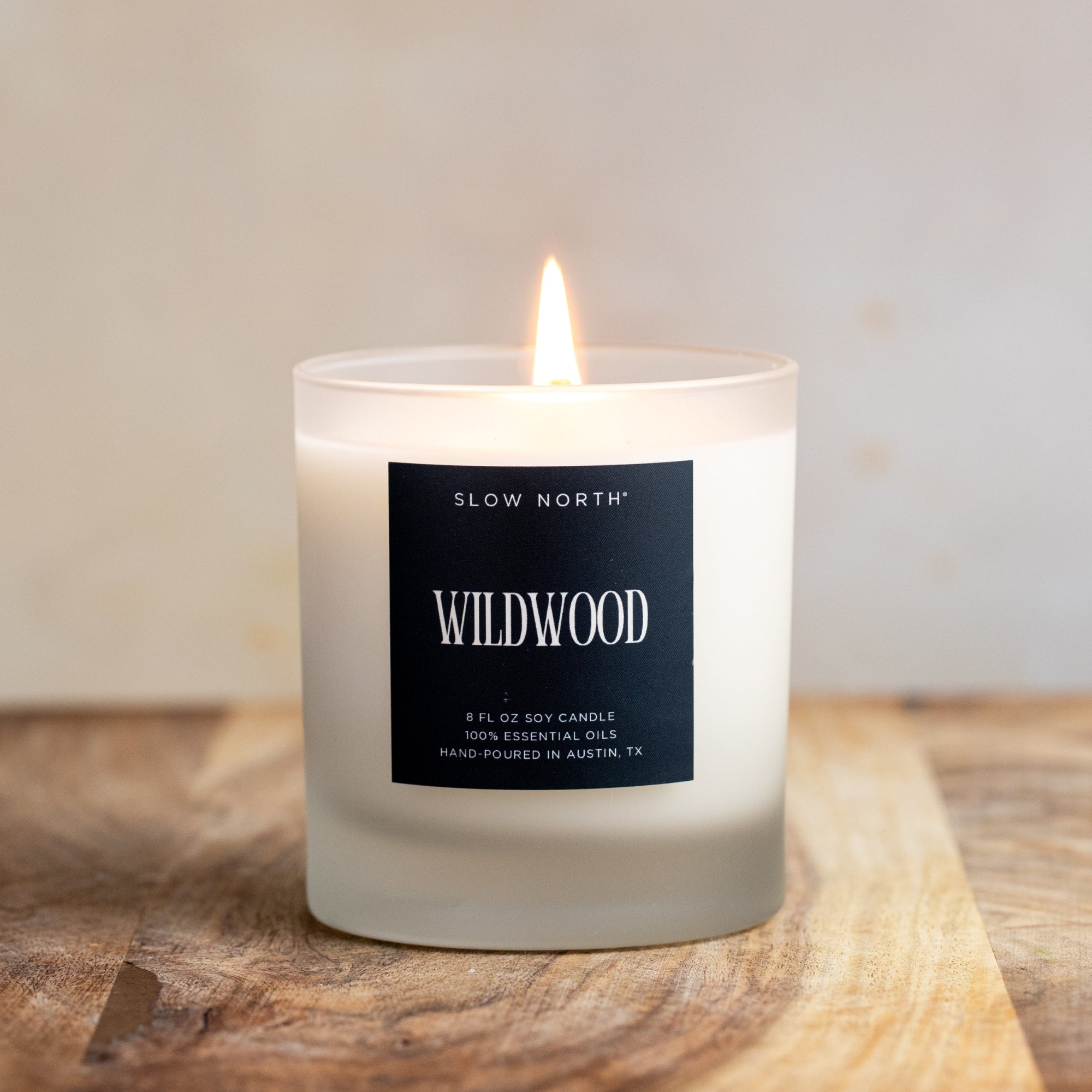 Candle with a 'Wildwood' label on a wooden surface