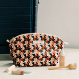 pink and red handcrafted gold zipper cosmetic bag surrounded by makeup