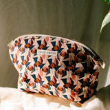 pink and red handcrafted gold zipper cosmetic bag in a green background