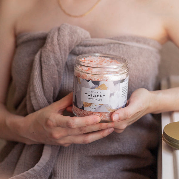 woman holding jar containing pink and purple bath salts