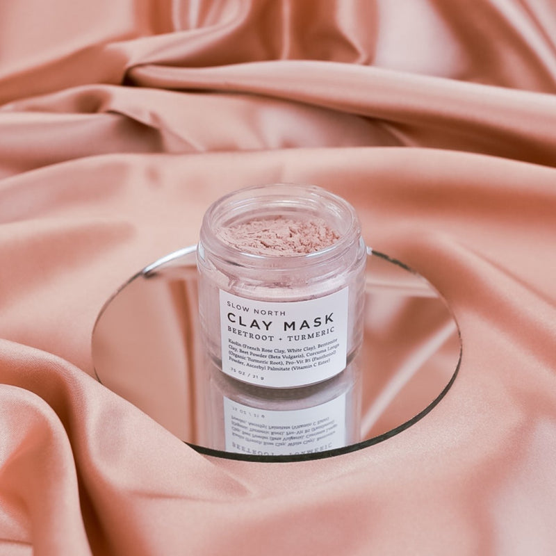 Beetroot + Turmeric Clay Mask .75 ounce in clear glass jar on pink silk fabric. By Slow North