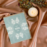 Sea-foam green with floral design Hand drawn 4.25" x 5.5" print greeting card. Next to lit 2 ounce candle and dried herbs. Best Mama Ever Card by Slow North