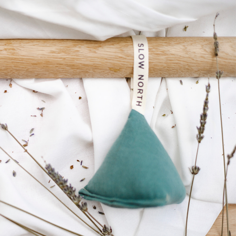 Lavender Sachet - Lagoon, a teal fabric sachet prism that is looped on a round wooden bar.