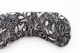 Black and cream fabric with assorted mushroom, crystal, and leaf patterns.