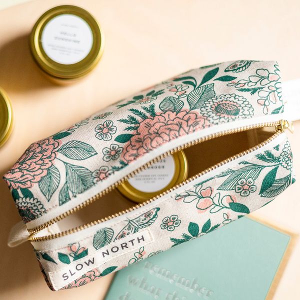 Hidden Falls green and pink floral pattern travel pouch with a gold 2oz candle inside of the bag